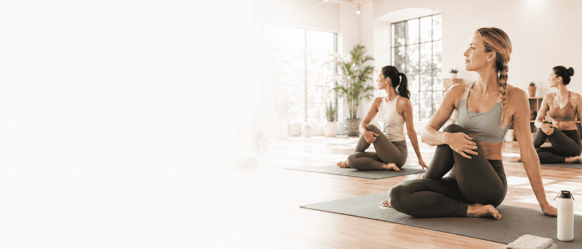 Yoga class practising seated twists in a bright, sunlit studio